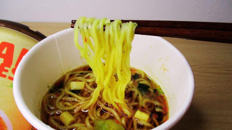 ヤマダイヴィーガンヌードル酸辣湯麵の麺を箸ですくう