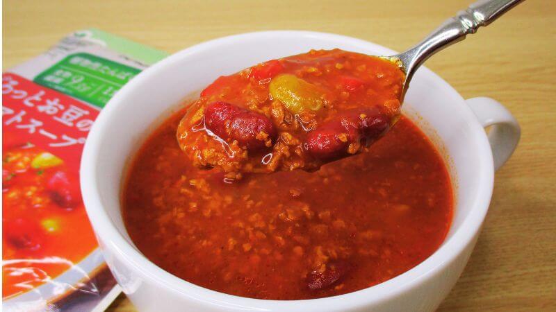 カゴメプラントベースごろっとお豆のチリトマトスープをスプーンですくう